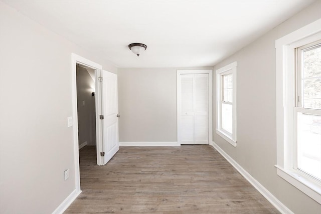 unfurnished bedroom with a closet, light wood-style flooring, and baseboards