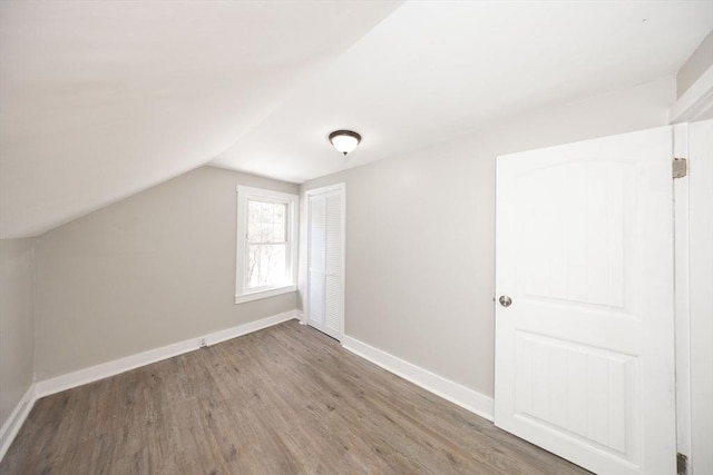 additional living space with baseboards, vaulted ceiling, and wood finished floors