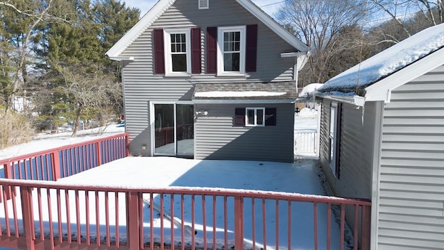 snow covered property with a shingled roof and a wooden deck