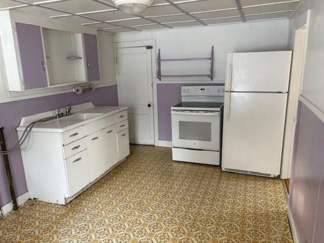 kitchen featuring white appliances, white cabinets, a drop ceiling, light countertops, and light floors