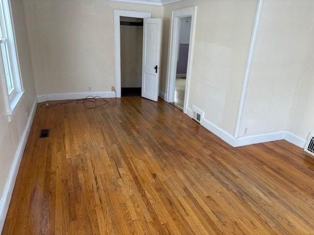 empty room with visible vents, baseboards, and wood finished floors