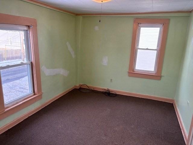 carpeted spare room with baseboards and crown molding