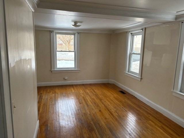 unfurnished room with visible vents, crown molding, baseboards, and wood finished floors