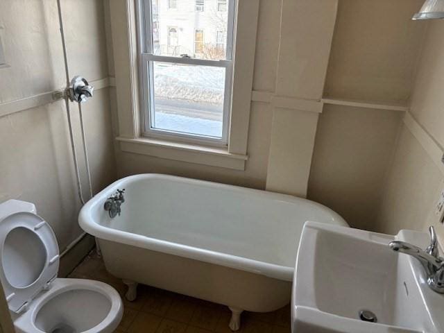 bathroom with toilet, a freestanding bath, and a sink