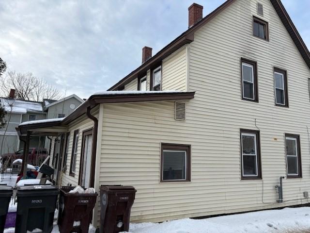 snow covered property featuring a chimney