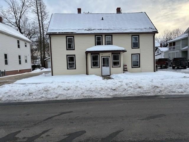 snow covered property with a chimney