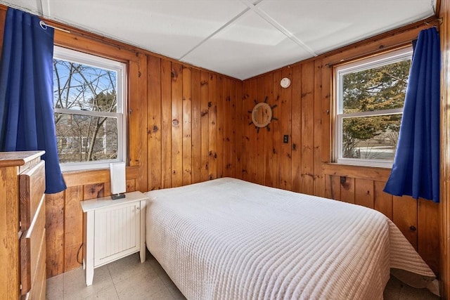 bedroom featuring wooden walls and multiple windows