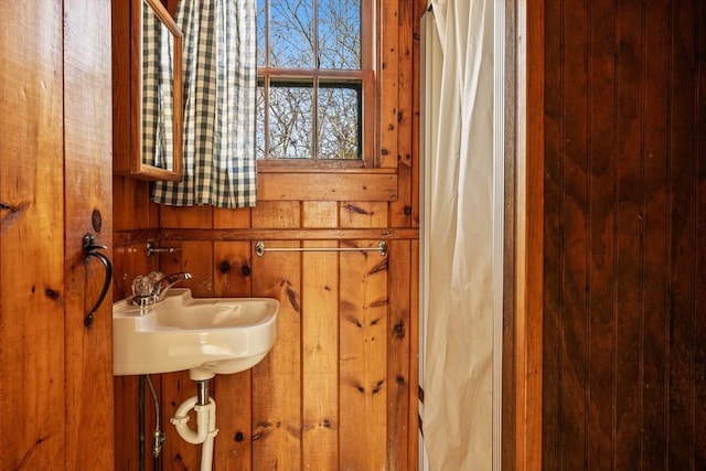 full bathroom with wood walls, a shower with curtain, and a sink