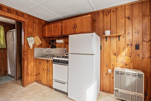 kitchen featuring brown cabinetry, white appliances, light countertops, and wood walls