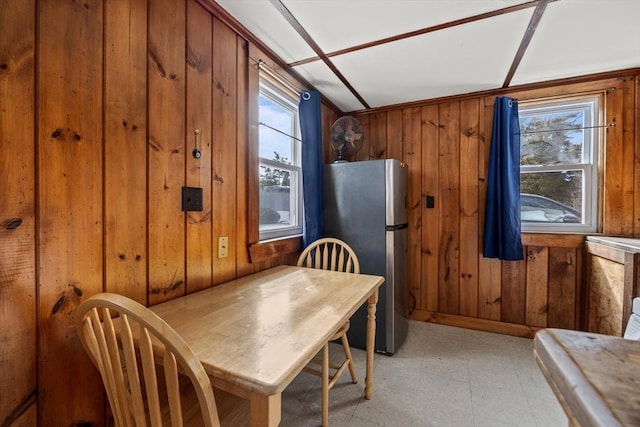 dining space with a healthy amount of sunlight, wood walls, and light floors