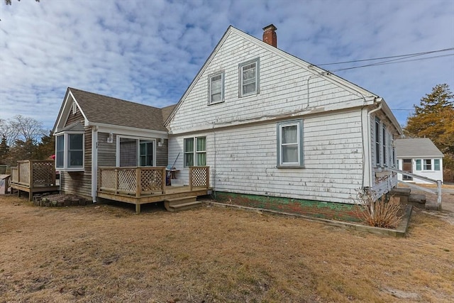 rear view of house with a shingled roof, a chimney, and a wooden deck