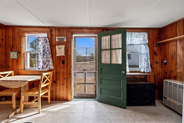 doorway to outside with heating unit and wooden walls