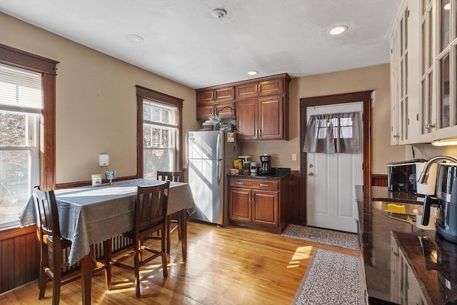 kitchen featuring glass insert cabinets, light wood-type flooring, recessed lighting, wainscoting, and freestanding refrigerator