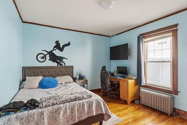 bedroom with baseboards, radiator, crown molding, and light wood finished floors