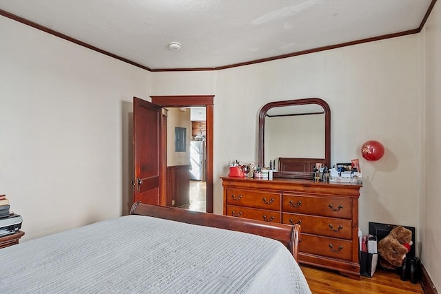 bedroom with ornamental molding and wood finished floors