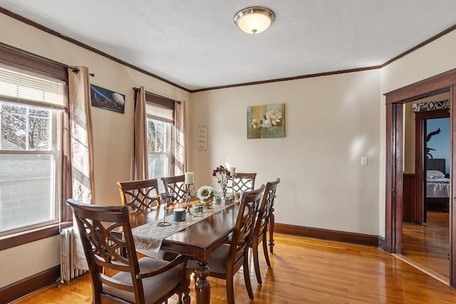 dining room with baseboards, light wood-type flooring, and ornamental molding