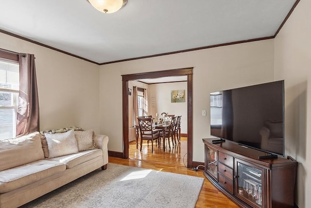 living area with baseboards, light wood-style flooring, and crown molding