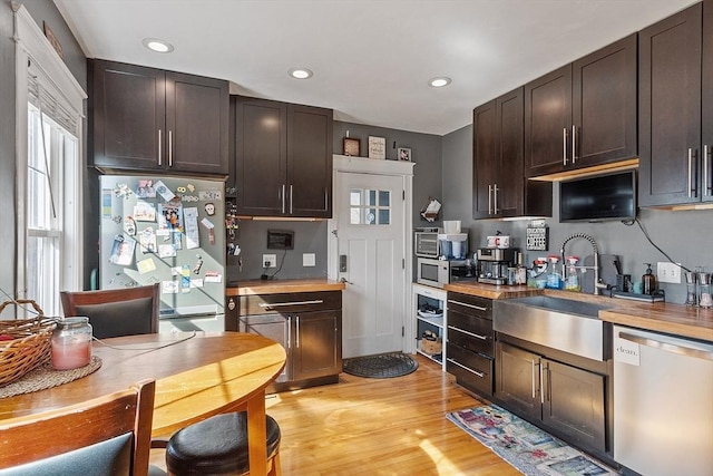 kitchen with a sink, recessed lighting, dark brown cabinetry, appliances with stainless steel finishes, and light wood finished floors