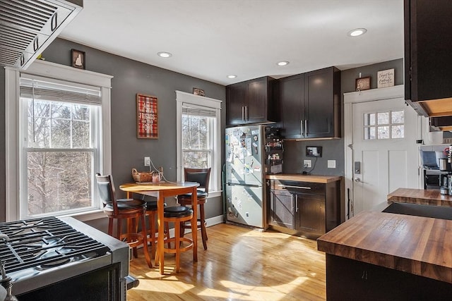 kitchen with light wood finished floors, recessed lighting, freestanding refrigerator, and butcher block counters