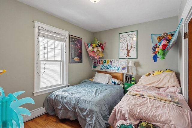 bedroom with a baseboard heating unit, baseboards, and wood finished floors