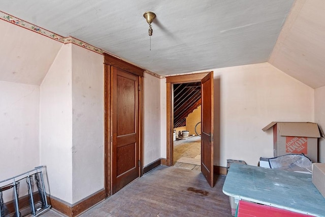 additional living space with baseboards, lofted ceiling, and wood finished floors