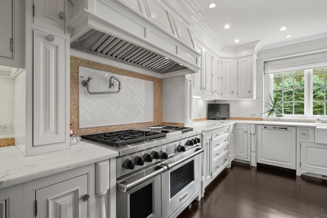 kitchen with range with two ovens, crown molding, white cabinets, premium range hood, and tasteful backsplash