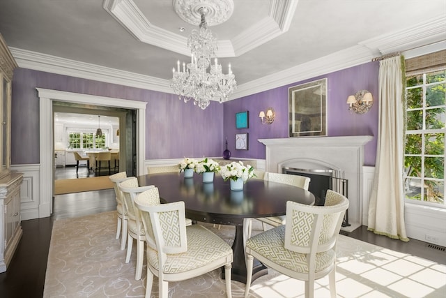 dining space featuring crown molding, a notable chandelier, wood-type flooring, and a tray ceiling