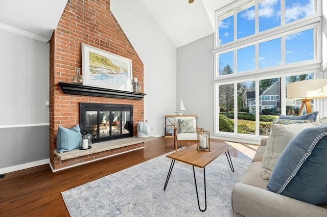 living room with crown molding, baseboards, a fireplace, wood finished floors, and high vaulted ceiling