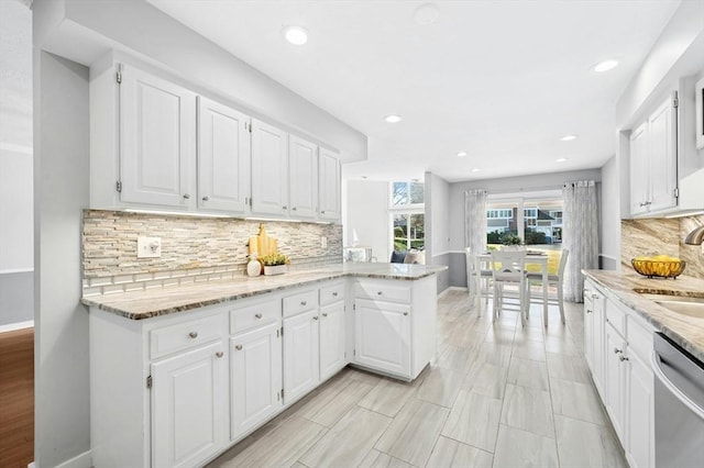 kitchen featuring light stone counters, white cabinetry, tasteful backsplash, and stainless steel dishwasher