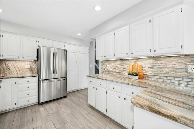 kitchen with light stone counters, white cabinets, and freestanding refrigerator