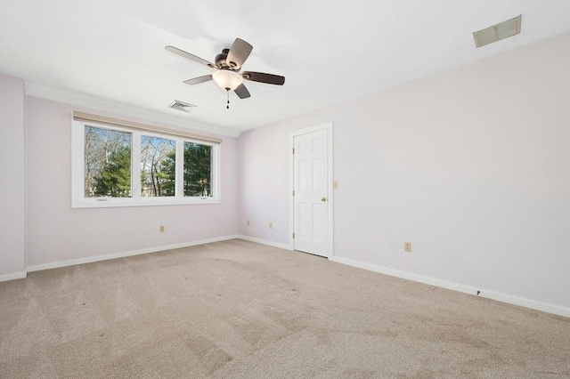 carpeted spare room featuring baseboards, visible vents, and ceiling fan