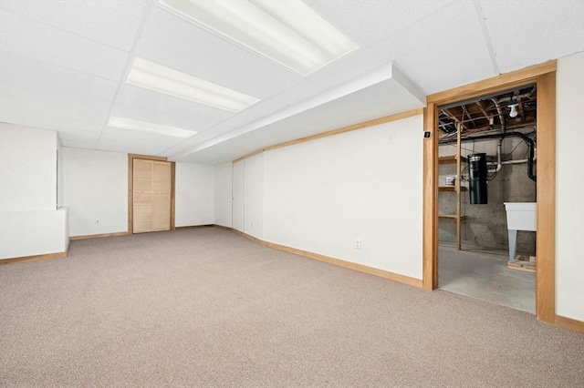 finished below grade area with a drop ceiling, light colored carpet, and baseboards