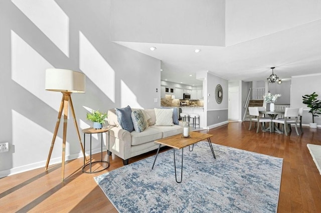 living room with wood finished floors, baseboards, an inviting chandelier, a high ceiling, and recessed lighting