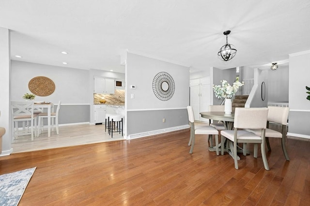 dining room with light wood finished floors, recessed lighting, an inviting chandelier, and baseboards