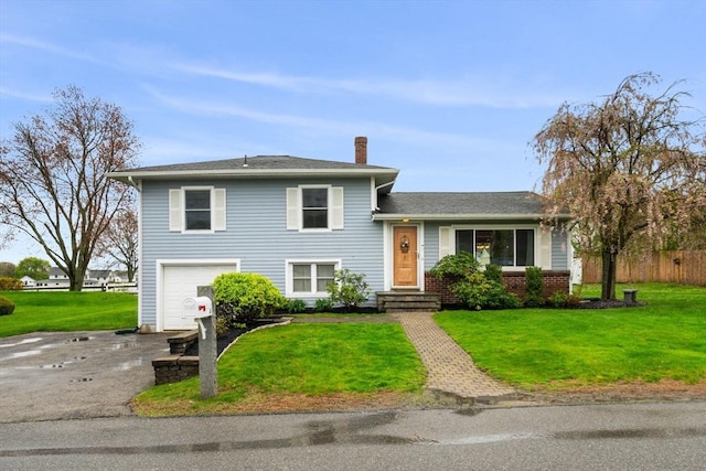 tri-level home featuring an attached garage, a front lawn, a chimney, and driveway