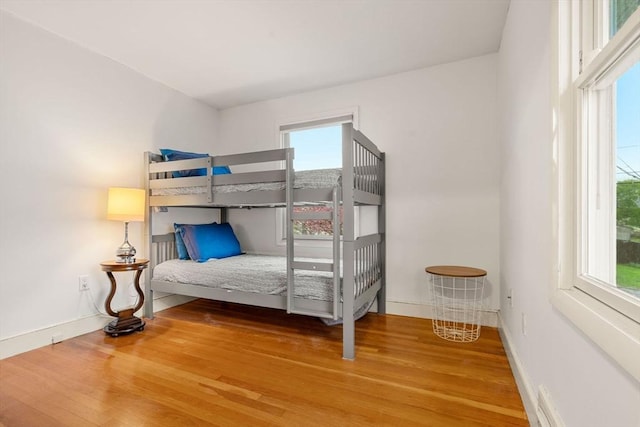 bedroom featuring multiple windows, wood finished floors, and baseboards