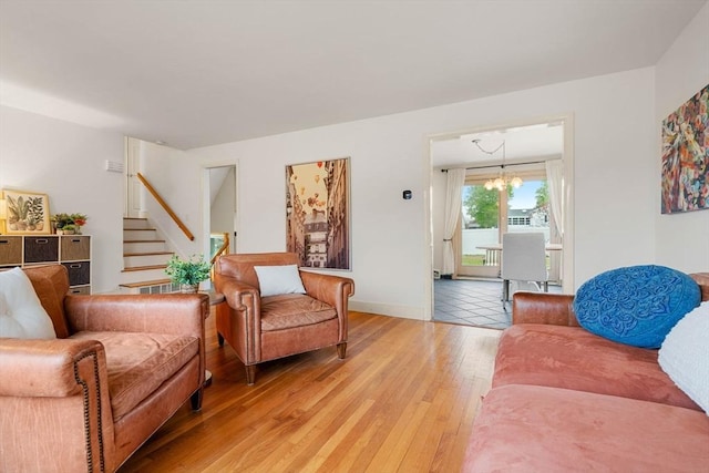 living room with a chandelier, stairway, light wood-style flooring, and baseboards