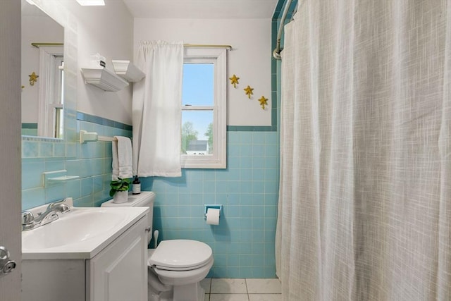 full bathroom with tile walls, toilet, tile patterned floors, vanity, and a wainscoted wall