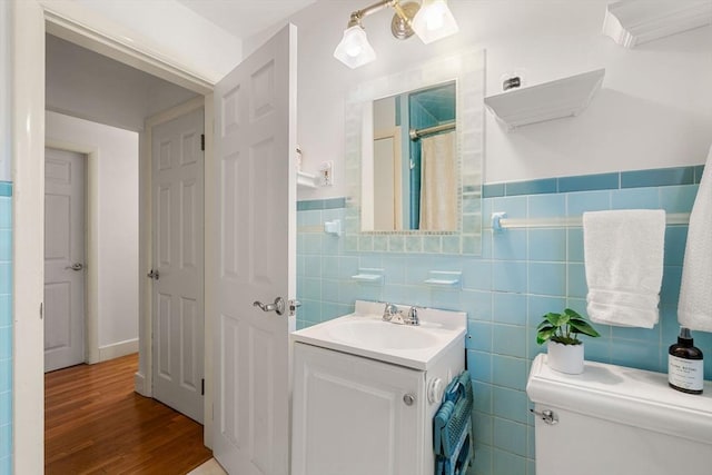 bathroom with tile walls, a shower with shower curtain, wood finished floors, and vanity