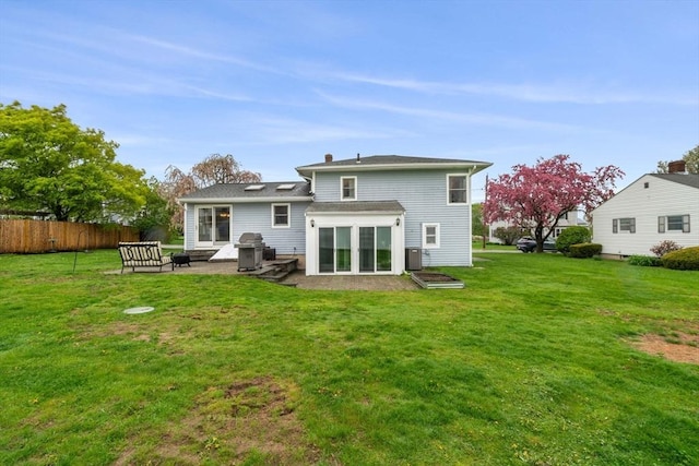 rear view of house featuring fence, a patio, and a lawn