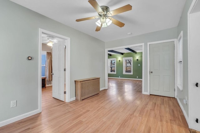 spare room with light wood-style floors, radiator heating unit, and baseboards