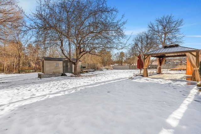 yard covered in snow with a storage unit, an outbuilding, and a gazebo