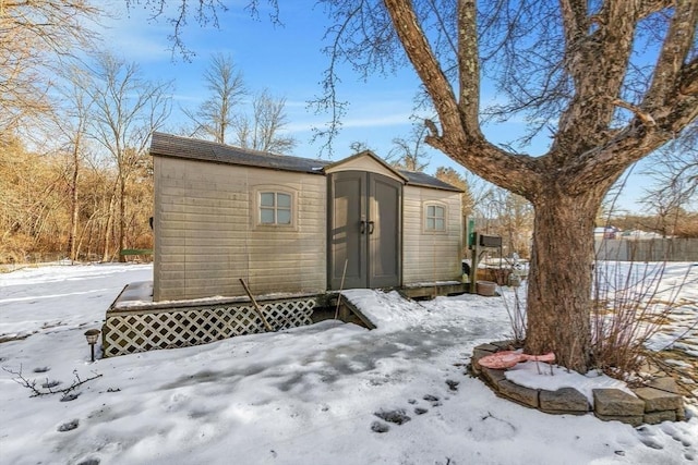 snow covered structure featuring a storage shed, fence, and an outdoor structure