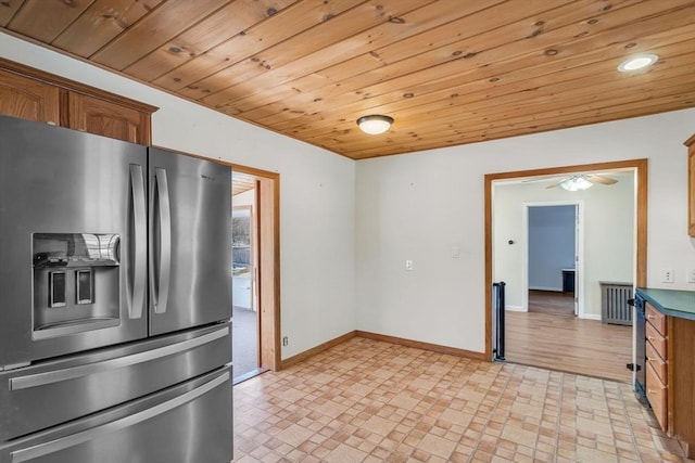 kitchen featuring brown cabinetry, stainless steel fridge, wood ceiling, and baseboards