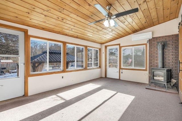 unfurnished sunroom with wood ceiling, a wood stove, a wall unit AC, and plenty of natural light