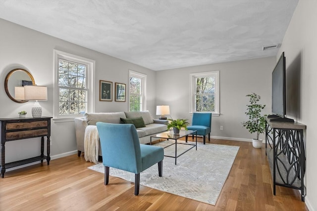 living area featuring baseboards, visible vents, and wood finished floors