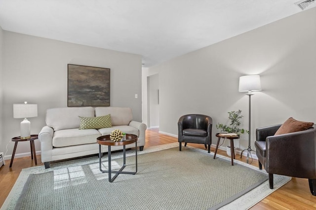 living room featuring baseboards, wood finished floors, and visible vents