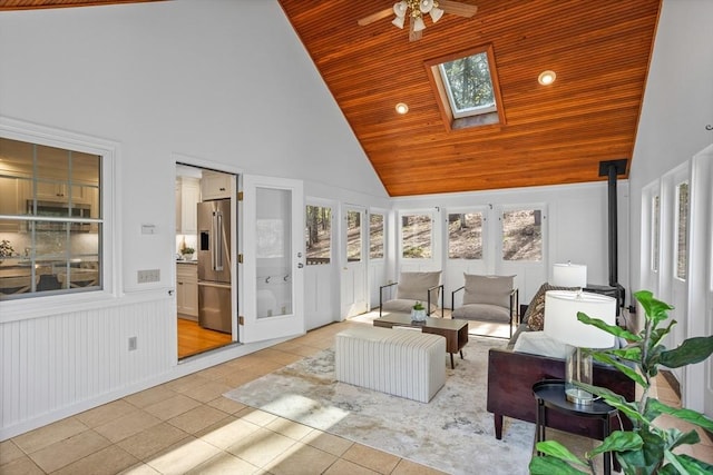 sunroom with a wood stove, high vaulted ceiling, tile patterned floors, wooden ceiling, and a skylight