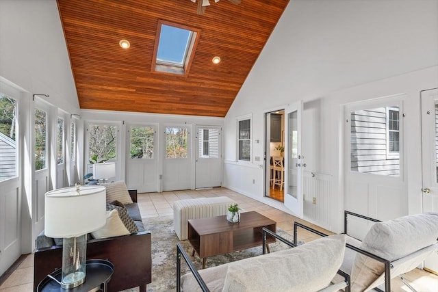 sunroom / solarium with wood ceiling, a skylight, tile patterned floors, high vaulted ceiling, and a decorative wall