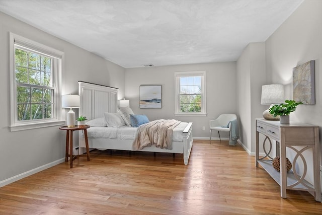 bedroom with visible vents, light wood-style flooring, and baseboards